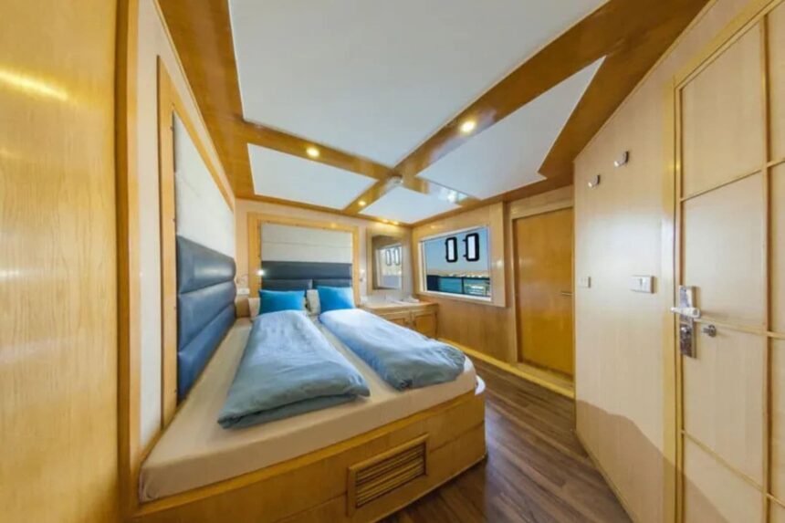 Twin cabin aboard the MY Blue Seas with wood paneling and blue bedding