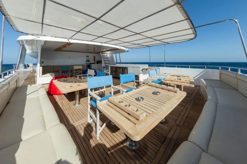 Shaded outdoor dining tables with blue director chairs on the MY Blue Seas top deck