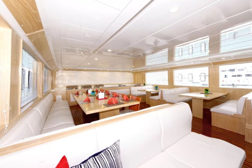 Interior dining salon with white booth seating and red accent pillows on the MY Blue Seas