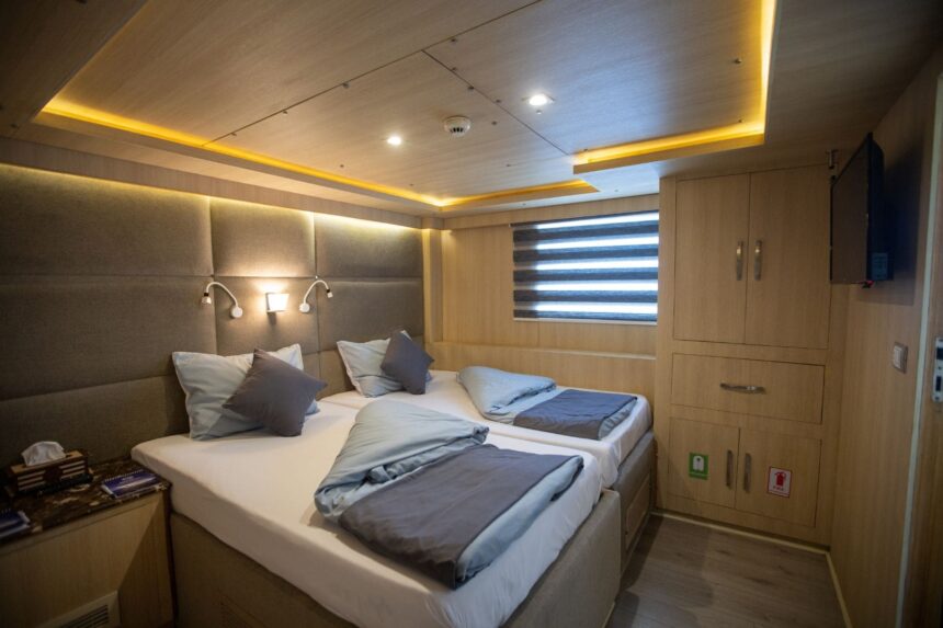 Twin cabin with gray bedding and wood cabinetry aboard the Captain Sparrow