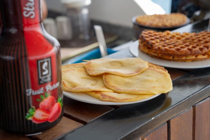 Pancakes and waffles plated beside a bottle of fruit puree syrup for breakfast