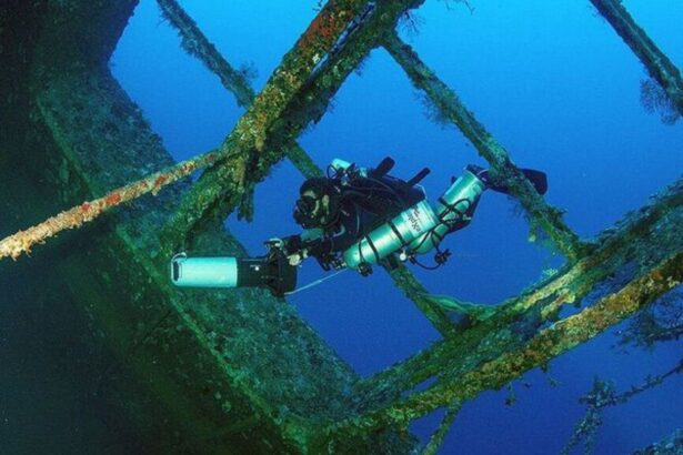 Diver photographing the rigging of a sunken shipwreck underwater