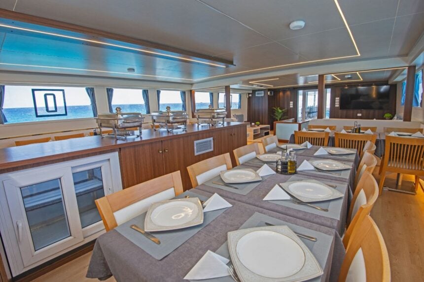 Dining area on the Dolce Vita with a wooden buffet counter, table settings and a wall TV