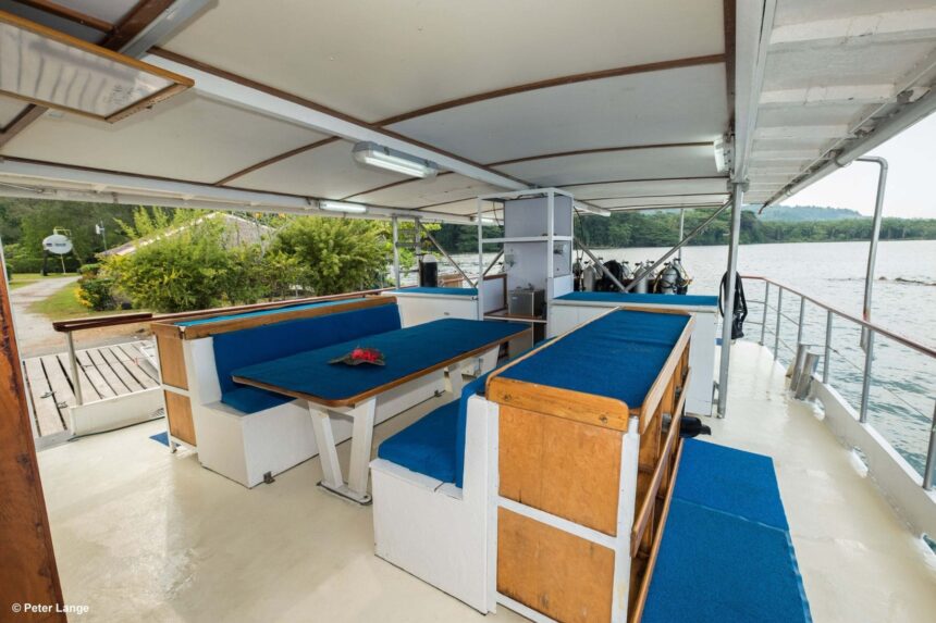 Covered outdoor lounge deck aboard the MV FeBrina with wooden bench seating
