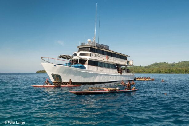 MV FeBrina liveaboard anchored with local outrigger canoes alongside