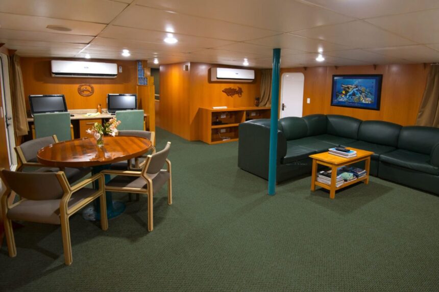 Lounge with dining table, sofas and TVs aboard the Odyssey liveaboard