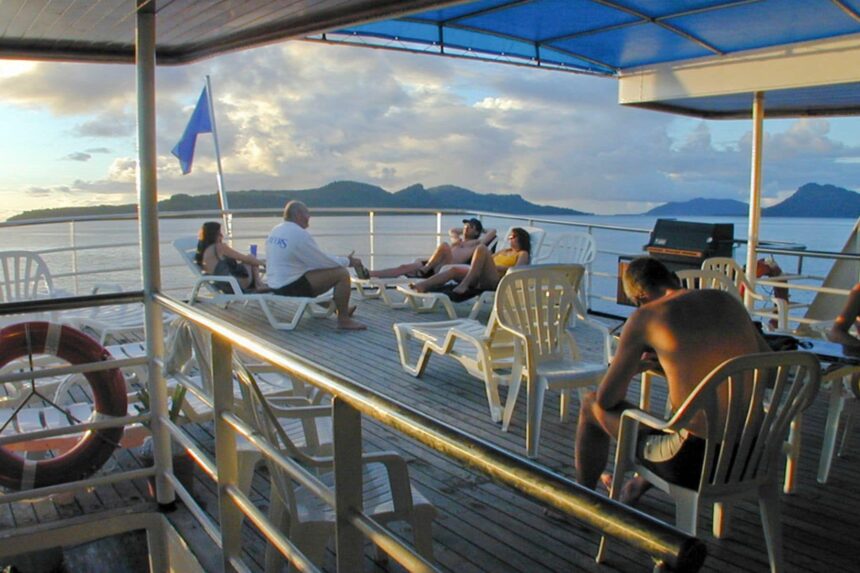 Guests relaxing in deck chairs on the Odyssey liveaboard at sunset