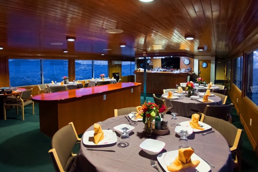 Formal dining room with round tables set for dinner aboard the Odyssey liveaboard