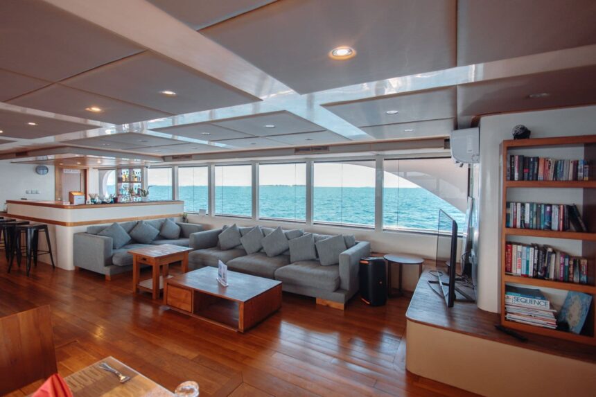Onboard lounge and bar area with sofas and a bookshelf on the Adora