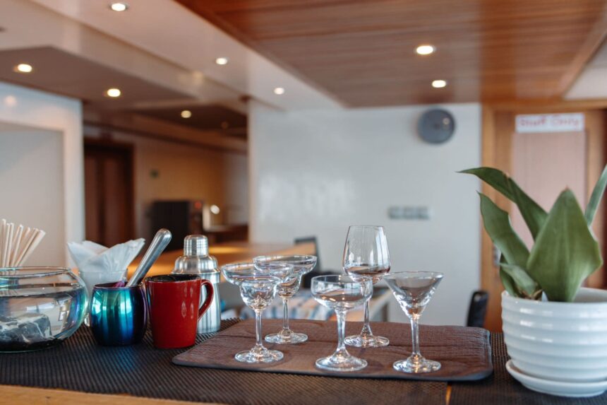 Bar counter set with cocktail glasses and a potted plant on the Adora