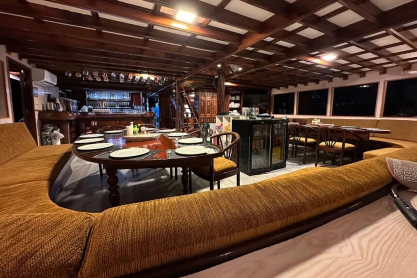 Formal dining room set up at night aboard the Amba with a bar in the background