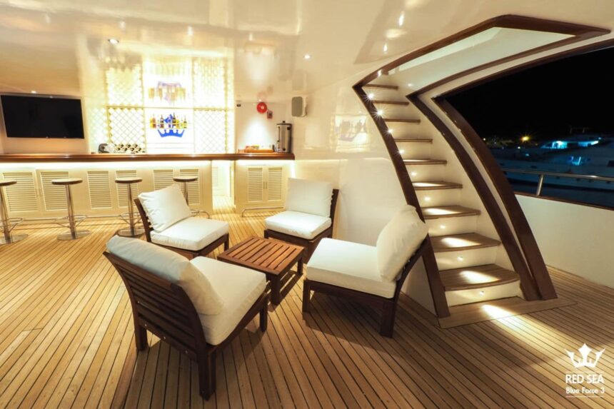Lounge chairs beside a staircase and bar on the Blue Force 3's evening deck
