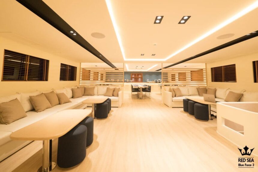Long indoor lounge with white sofas leading to the dining area on the Blue Force 3