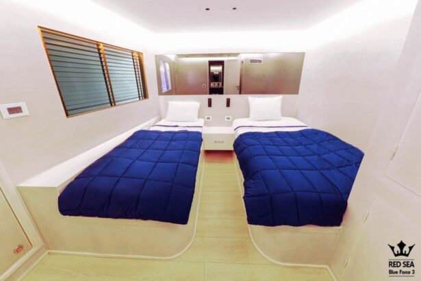 Twin cabin aboard the Blue Force 3 with navy bedspreads reflected in a mirrored wall