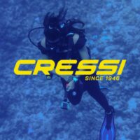 Scuba diver in black gear over a reef, overlaid with the Cressi since 1946 logo