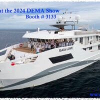 Gaia Love liveaboard yacht with a banner inviting divers to DEMA 2024 booth 3133
