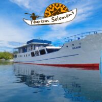 Bilikiki liveaboard dive boat anchored near shore, overlaid with the Tourism Solomons logo