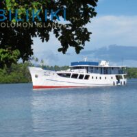 Bilikiki liveaboard boat anchored in a lagoon framed by mangroves, with the Bilikiki Solomon Islands logo