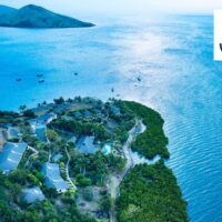 Aerial view of Volivoli Beach Resort's Fiji coastline with boats anchored offshore