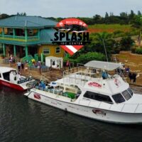 Aerial view of Splash Dive Center's Belize dock with the company's dive flag logo overlaid on the scene