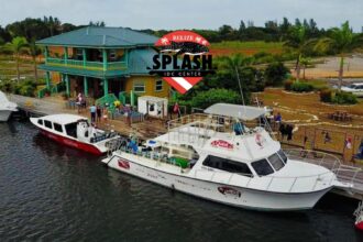 Aerial view of Splash Dive Center's Belize dock with the company's dive flag logo overlaid on the scene