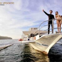 Three divers posing on the stern of a Marco Vincent Philippines outrigger boat at sunset