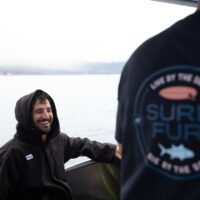 Two divers on a boat, one in a Surf Fur hooded changing robe, the other in a Surf Fur branded T-shirt