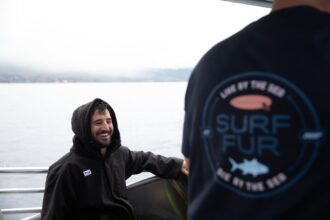 Two divers on a boat, one in a Surf Fur hooded changing robe, the other in a Surf Fur branded T-shirt