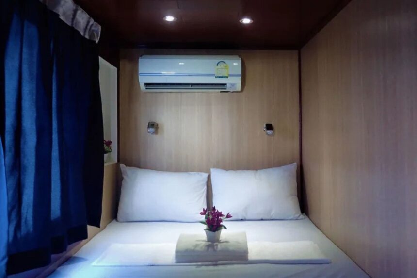cabin bed with blue curtain and a small flower vase on the pillow