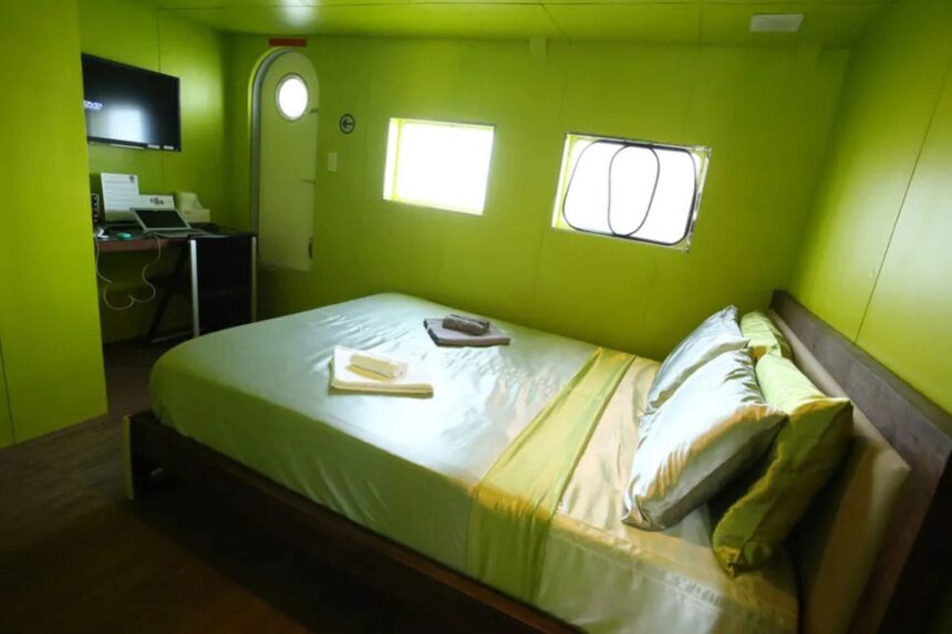 Green cabin aboard Stella Maris Explorer with a queen bed and desk