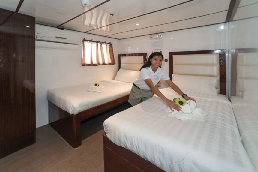crew member preparing a twin cabin aboard Discovery Palawan with folded towel art