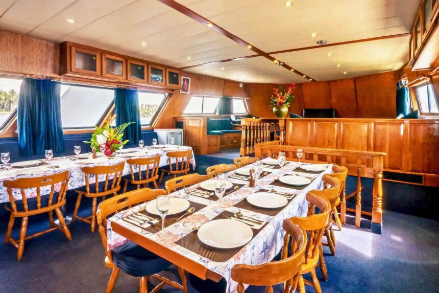 wood paneled dining room set for a meal aboard Atlantis Adventurer