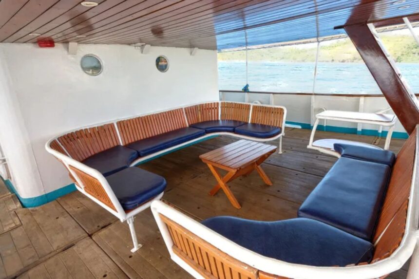 Wooden bench seating with blue cushions on the M/Y Resolute deck