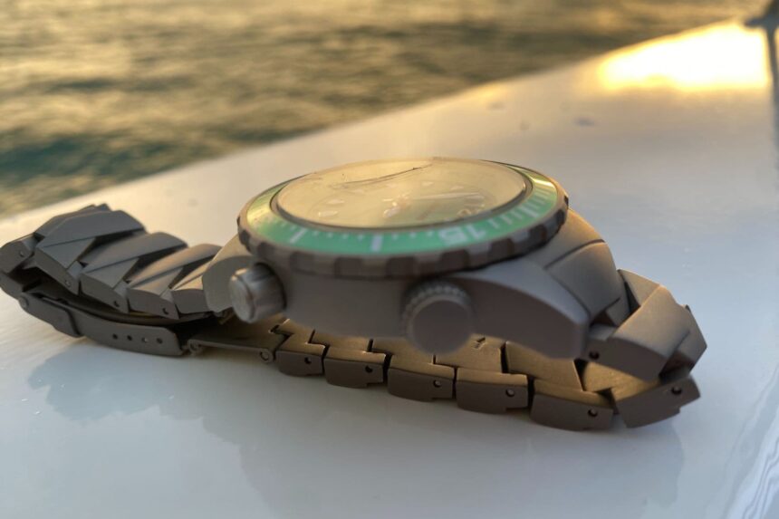 Abingdon Marina dive watch lying on its side on a boat deck, showing the green bezel and titanium bracelet