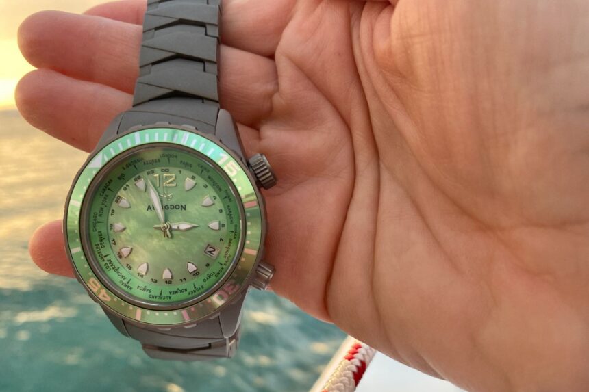 Our tester holding the Abingdon Marina dive watch with its green mother of pearl dial above the water at sunset