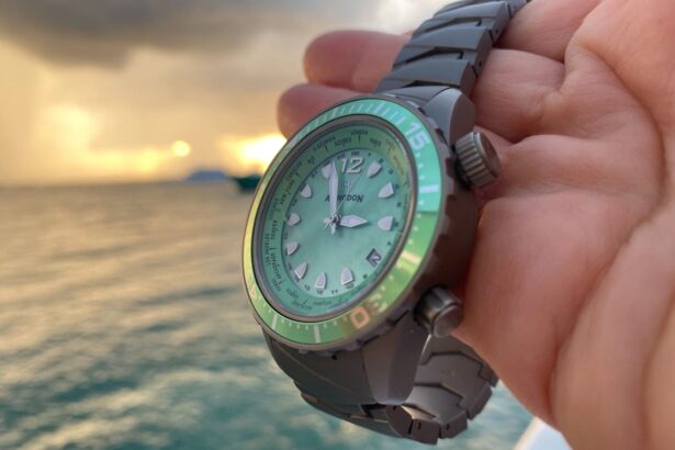 Our tester holding the Abingdon Co. Marina dive watch with its green dial and bezel against a sunset at sea