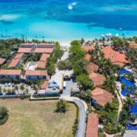 Aerial view of Mayan Princess Dive & Beach Resort's red-roofed villas and pool nestled among palms