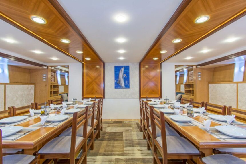 formal dining room with wooden tables set for guests aboard the Golden Dolphin III