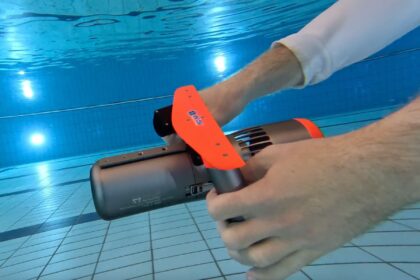 DIVEIN tester gripping the orange and grey Edge Smart Drive K5 scooter during a pool test