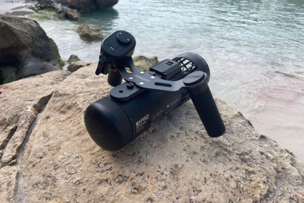LEFEET S1 Pro underwater scooter with its handle and remote sitting on a rock at the shoreline