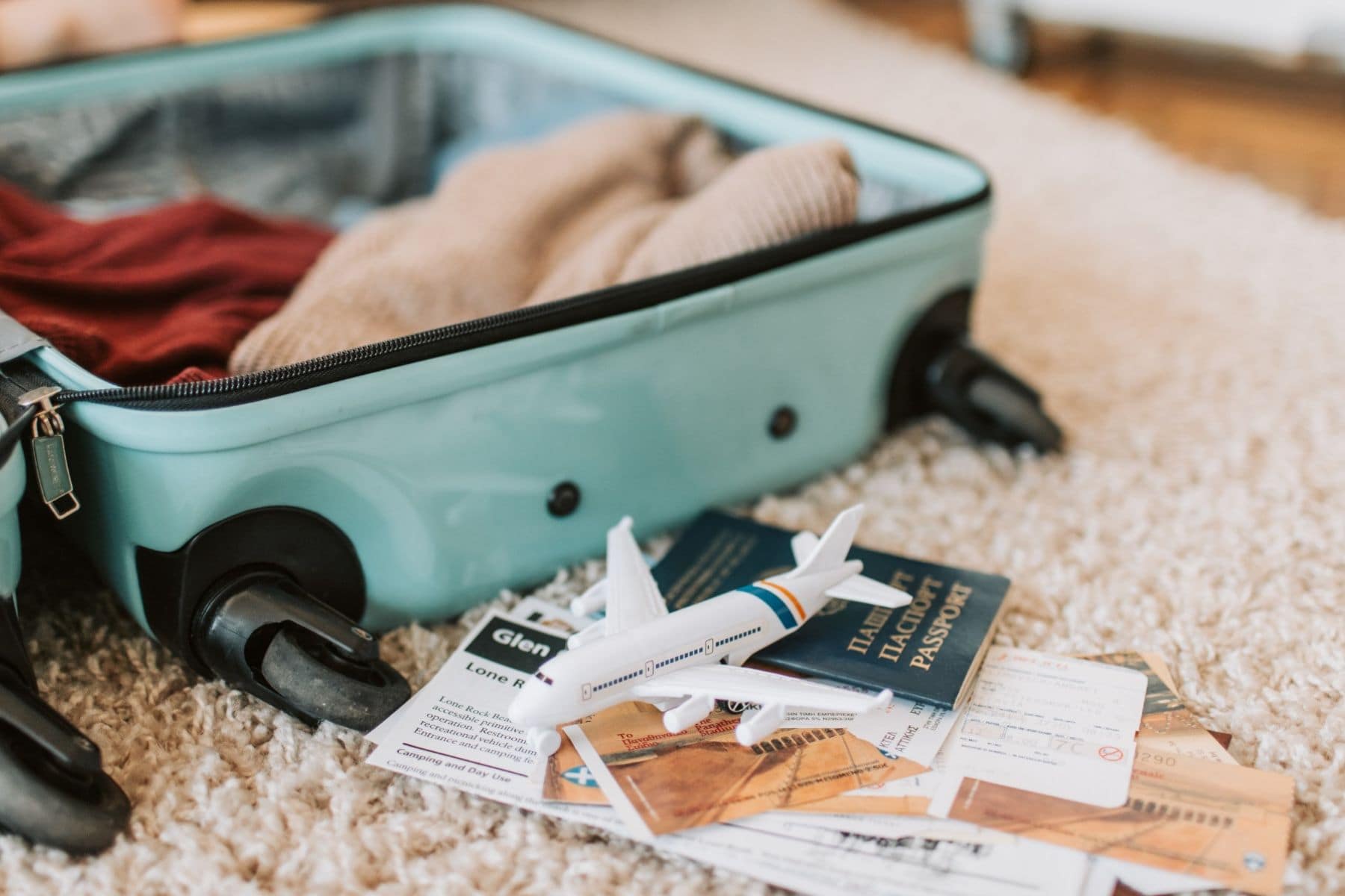 packed suitcase with a toy airplane and travel documents on a rug