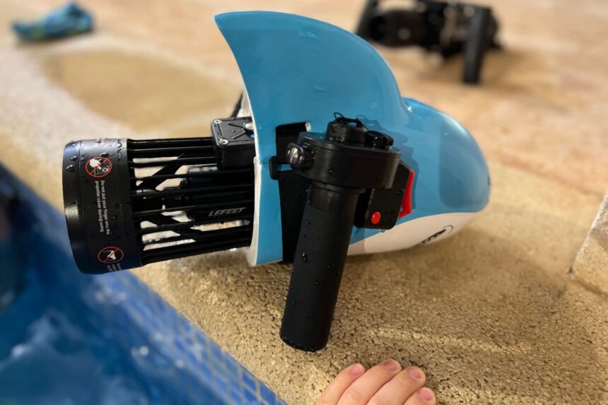 LEFEET S1 Pro motor and handle fitted to a blue shark-shaped float body at the edge of a pool