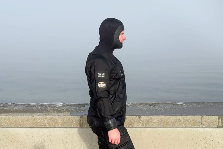 Otter Britannic Mk2 Side View Side view of our tester in the black Otter Britannic Mk2 Telescopic drysuit and hood on a foggy shore