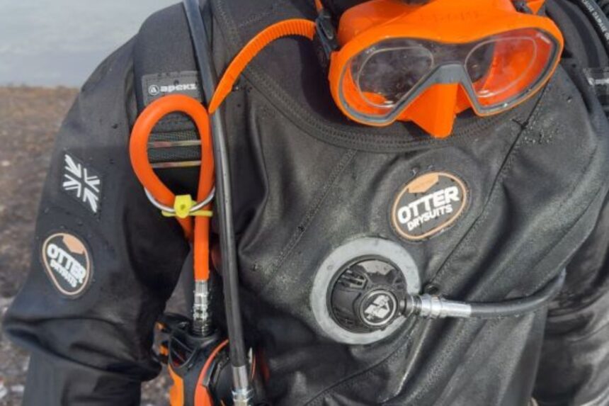 Otter Britannic Mk2 Front Detail Front of the Otter Britannic Mk2 Telescopic drysuit with chest inflator valve and orange mask on the hood