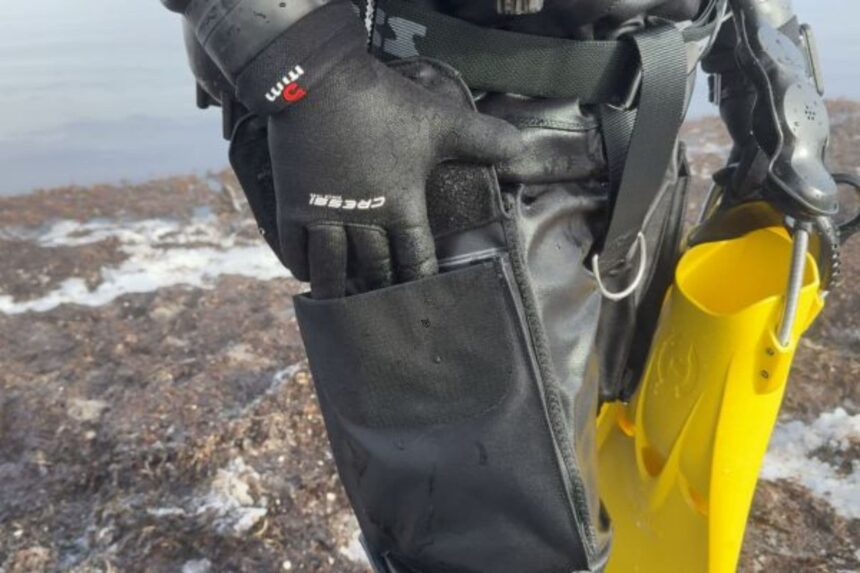 Otter Britannic Mk2 Thigh Pocket Gloved hand at the black thigh pocket of the Otter Britannic Mk2 Telescopic drysuit, fins alongside