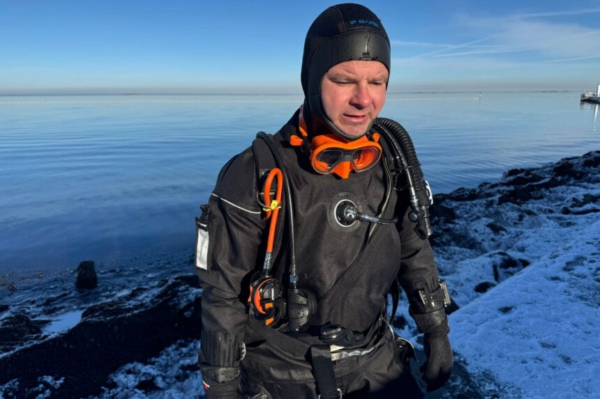 DIVEIN tester in the Northern Diver HID drysuit at a frozen shoreline with the chest valve in view