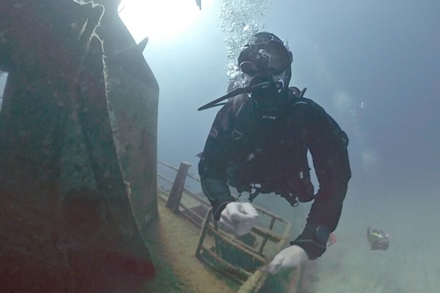 BARE X-Mission Evolution Wreck Dive DIVEIN tester swimming past a wreck structure in the BARE X-Mission Evolution drysuit