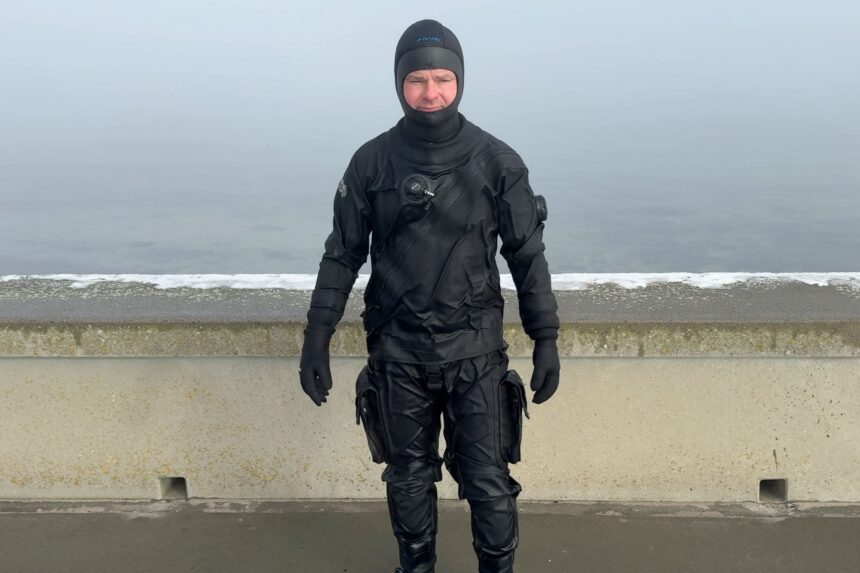 BARE X-Mission Evolution Thigh Pockets DIVEIN tester in the BARE X-Mission Evolution drysuit showing the thigh cargo pockets on a foggy shore