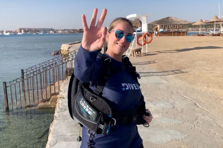 Cressi Elettra Tester Verdict Our tester raising a hand on a sunny beach wearing the Cressi Elettra BCD over a DIVEIN top