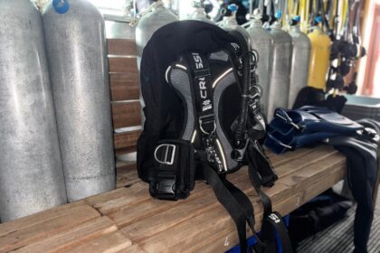 Cressi Aquawing Max backplate and wing rigged on a dive boat bench beside a row of filled tanks